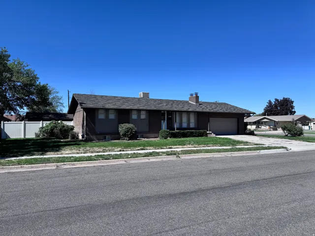 Ranch-style residence featuring a dark shingle roof, attached single-car garage, and a front lawn with mature shrubbery