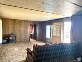 Wood-panel walls, carpet, front door, and a wood-burning stove. Located in the manufactured home.