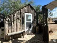 Shed with a pitched roof featuring a white-framed door and a wooden deck