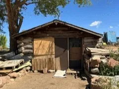 Woodshed surrounded by dirt and could be used as storage or possible root cellar.