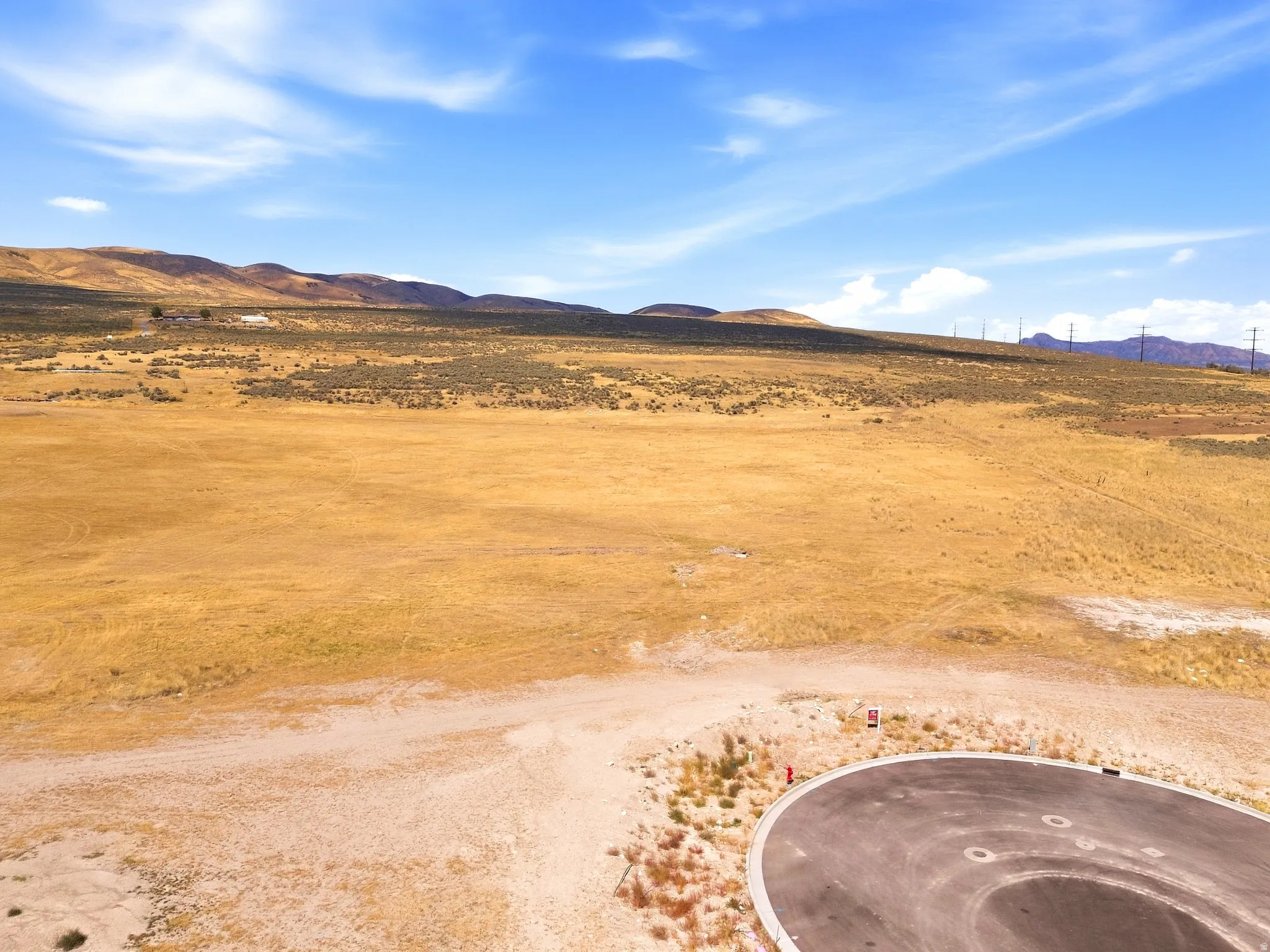 Expansive undeveloped land with distant rolling hills and a distinct cul-de-sac