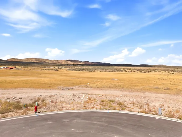 Paved cul-de-sac, bordered by a vast open landscape with distant rolling hills