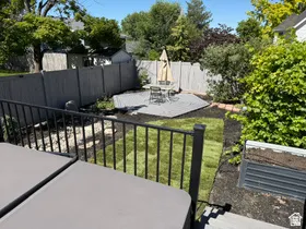Private outdoor space featuring a composite deck, fenced perimeter, manicured lawn, and raised planting bed