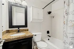 Vanity with granite countertop and undermount sink, framed mirror, built-in medicine cabinet, and built-in bathtub with shower
