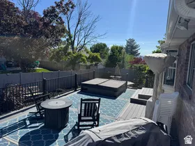 Spacious outdoor deck featuring a hot tub, composite decking, and a privacy fence
