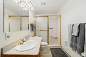 Vanity with an integrated sink and gold-tone faucet, framed mirror, and built-in shower with gold-tone sliding glass doors