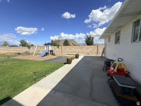 Spacious backyard featuring a manicured lawn, concrete patio, and privacy wall
