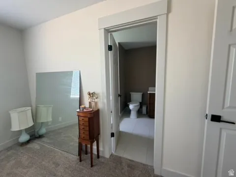 Carpeted room with a doorway featuring white trim and a white paneled door with matte black hardware