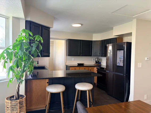 Kitchen featuring black cabinetry, black countertops, a built-in breakfast bar, and wood-finish lower cabinetry