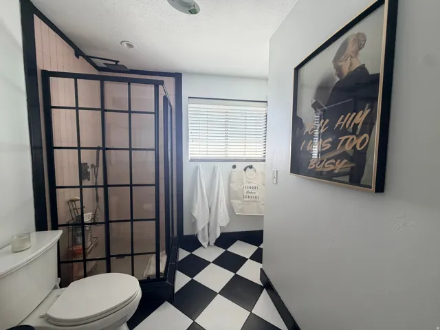 Walk-in shower with black grid-patterned enclosure and pink tiled walls