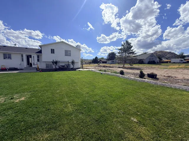 Expansive lawn area with a concrete patio and steps leading to the home