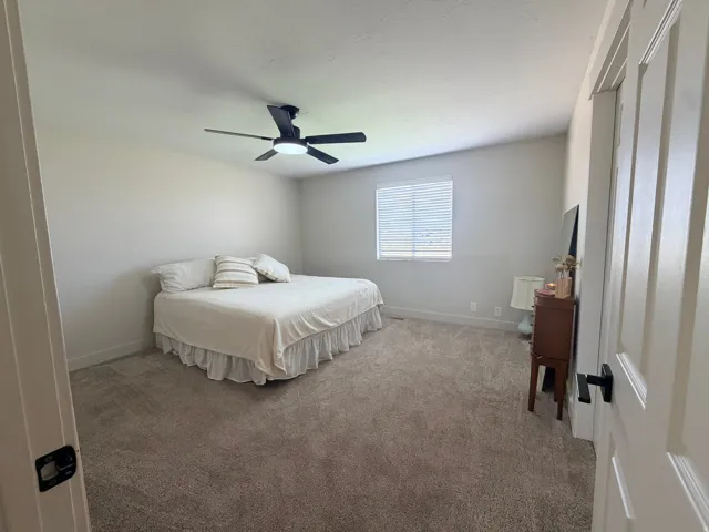 Plush carpet flooring, neutral wall tones, and a ceiling fan with integrated lighting