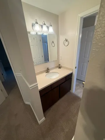 Elegant bathroom vanity featuring a single-sink design with a light wood-finish countertop, dark wood cabinetry with ample storage, and chrome fixtures