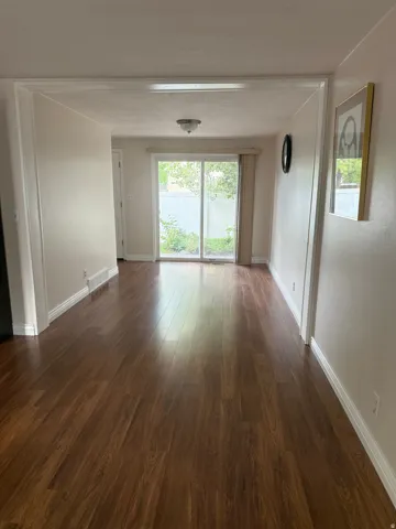 Wood-finish flooring throughout, framed doorway, sliding glass door, overhead flush mount light fixture