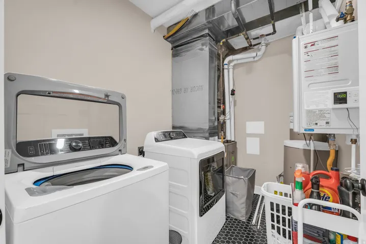 ADU Utility area featuring hexagonal floor tiling, wall-mounted water heater, and exposed ductwork