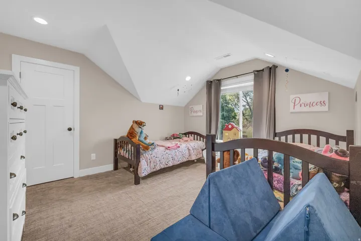 Recessed lighting illuminates the carpeted flooring and sloped ceiling