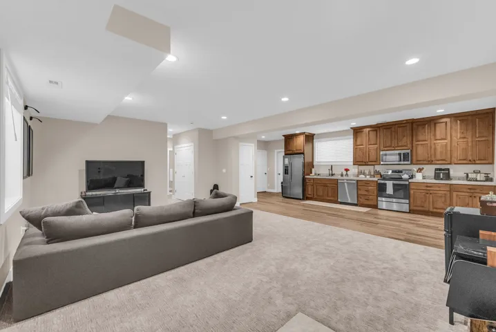 ADU Open-concept living space featuring recessed lighting, wood-finish flooring, and a kitchen with wood cabinetry and stainless steel appliances