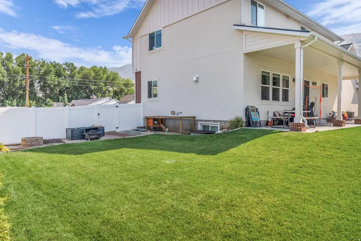 Expansive green lawn with a white vinyl fence, covered patio with white columns.