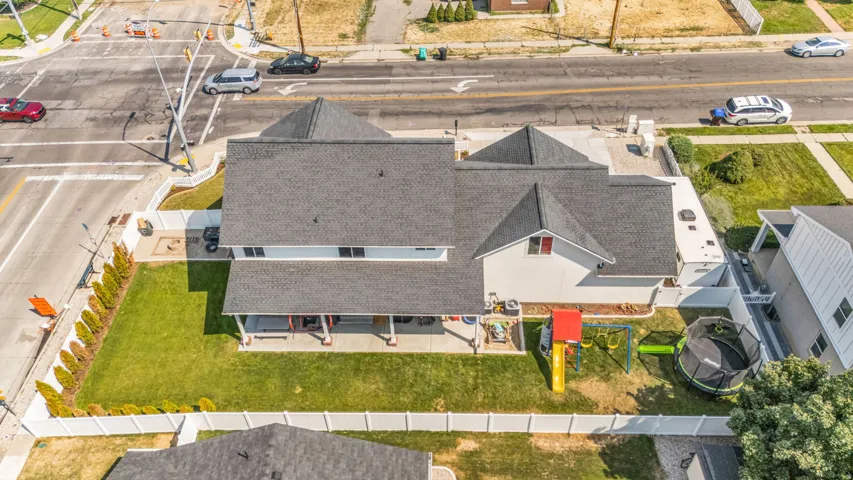 Expansive backyard with a manicured lawn, established landscaping, and a covered patio