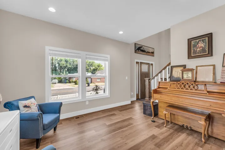 Wood-finish flooring throughout, recessed lighting, and a prominent staircase with white balusters