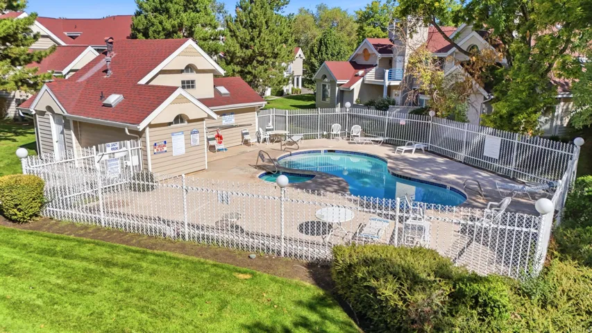 Fenced swimming pool with surrounding patio area and adjacent pool house