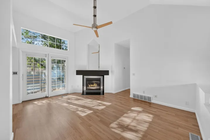 Vaulted ceiling, wood-finish flooring, built-in fireplace with mantel, ceiling fan, and Sliding Glass Doors with transom windows