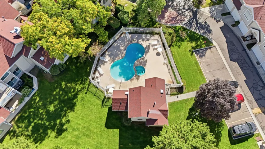 Community pool with an integrated spa, surrounded by a fenced patio and adjacent to green spaces