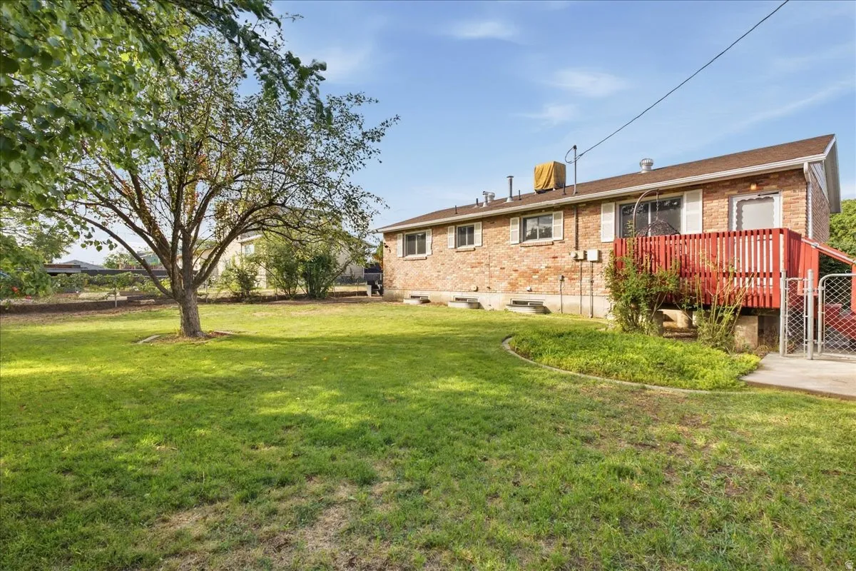 Expansive grassy yard with mature tree and red brick exterior