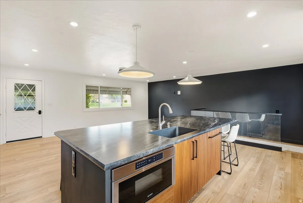 Kitchen island with built-in stainless steel microwave, integrated sink, and stone-finish countertop