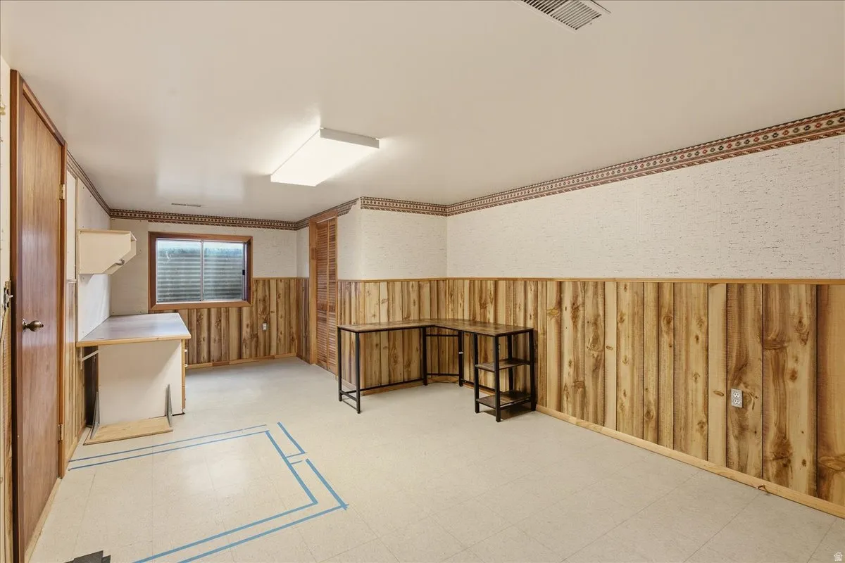 Recessed window, wood-paneled walls, built-in cabinetry, overhead fluorescent lighting, and a neutral flooring