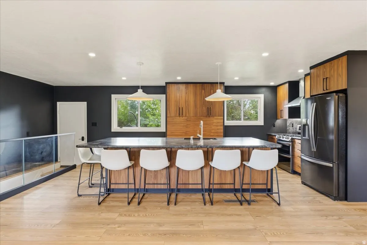 Gourmet kitchen with a large central island, wood-finish cabinetry, stainless steel appliances, and wood-finish flooring