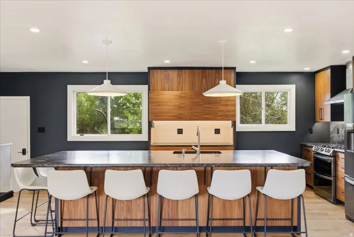 Kitchen featuring an expansive island with seating, wood-finish cabinetry, stainless steel appliances, and recessed lighting