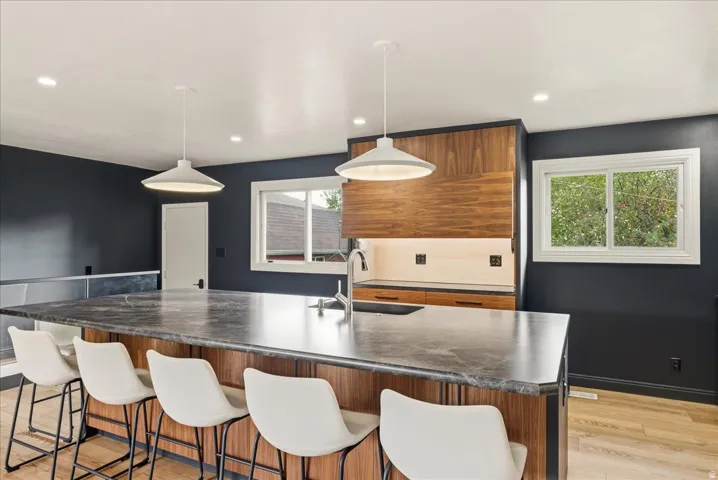 Expansive kitchen island with a dark stone countertop, wood-finish cabinetry, and integrated sink