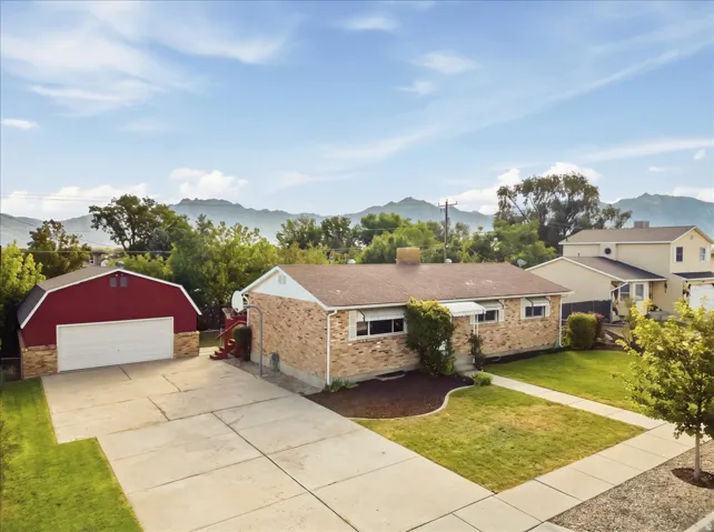 Brick exterior with a detached red barn-style garage, concrete driveway, and front lawn