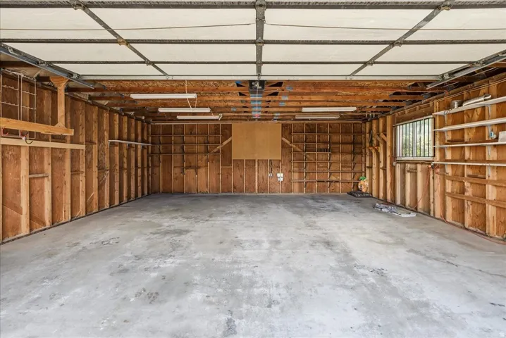 Exposed wood framing with built-in shelving, concrete flooring, and a single window