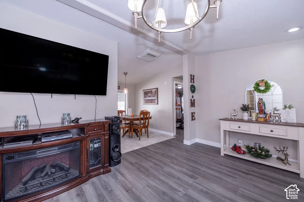 Wood-finish flooring, recessed lighting, and a contemporary chandelier illuminate this space