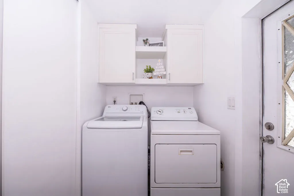 Dedicated laundry area featuring a top-load washer, front-load dryer, and white shaker-style cabinetry with open shelving