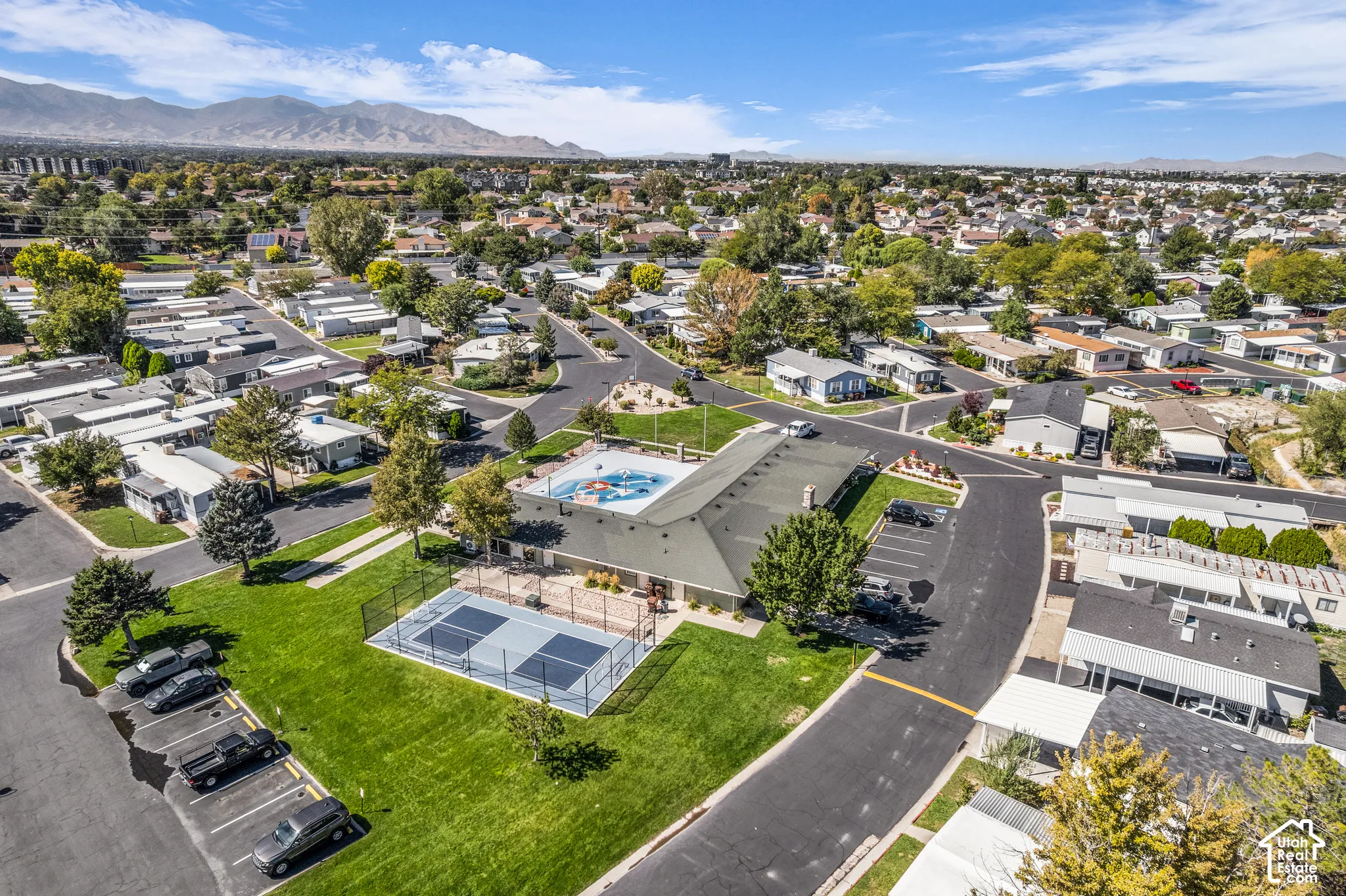 Community recreational building with an outdoor pool, fenced sports court, and adjacent paved parking