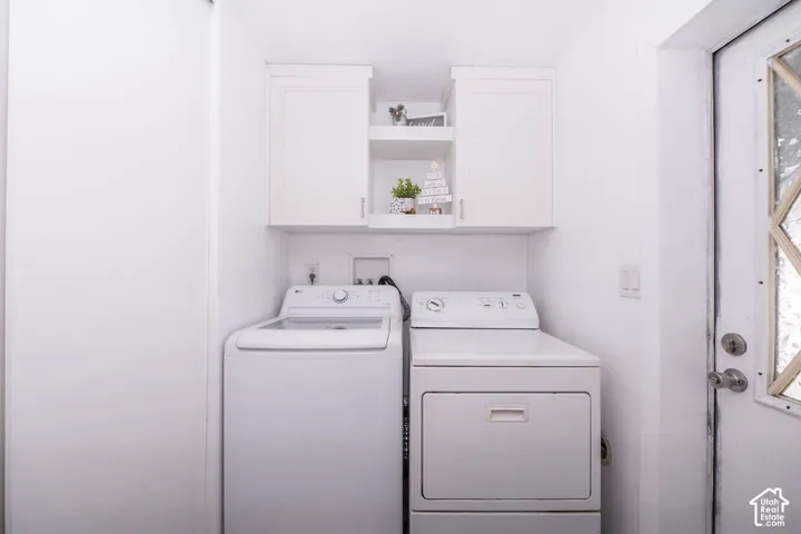 Dedicated laundry area featuring a top-load washer, front-load dryer, and white shaker-style cabinetry with open shelving