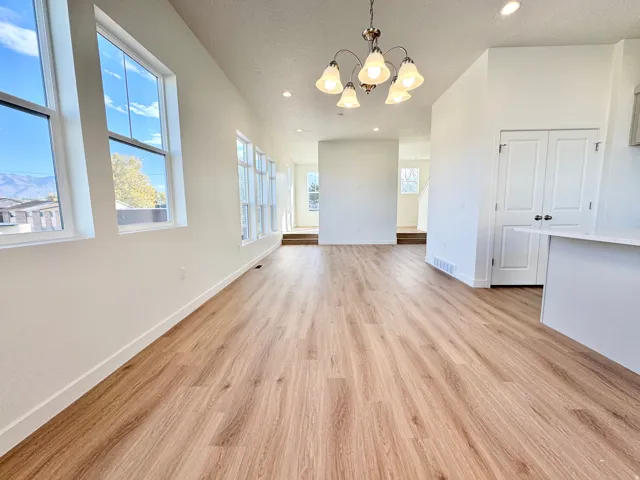 Expansive room featuring wood-finish flooring, multiple windows, a decorative chandelier, and recessed lighting