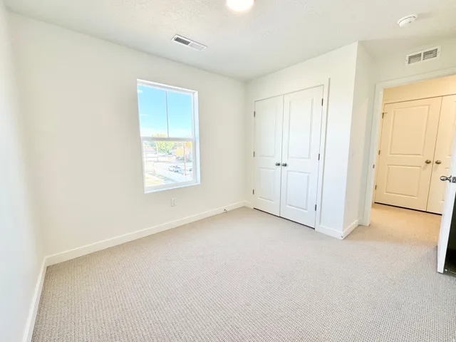 Recessed ceiling light, wall-to-wall carpeting, white interior walls, white trim, and a white bi-fold closet