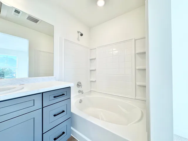 Built-in tub with wall-mounted shower fixture and integrated shelving