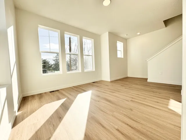 Neutral wall tones, wood-finish flooring, recessed ceiling lighting, and multiple windows
