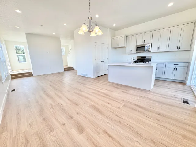 Open-concept living space with light wood-finish flooring, recessed lighting, and a modern kitchen