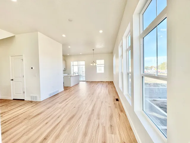 Open-concept living area featuring wood-finish flooring, recessed lighting, and multiple large windows