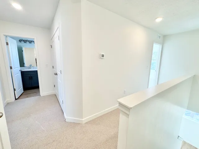 Contemporary interior with recessed lighting, light neutral carpet, and a white painted banister