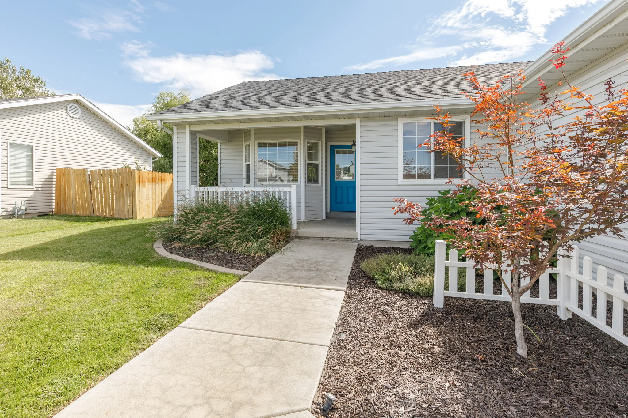 Exterior featuring light-colored siding, a covered porch, and a vibrant blue entry door