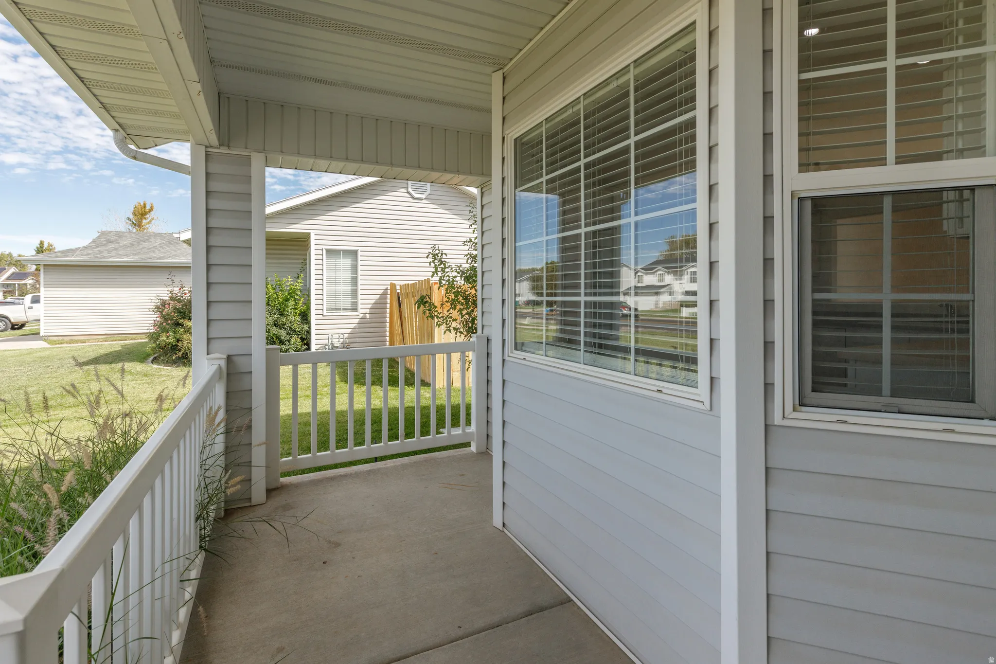 Covered front porch with concrete flooring and white railing