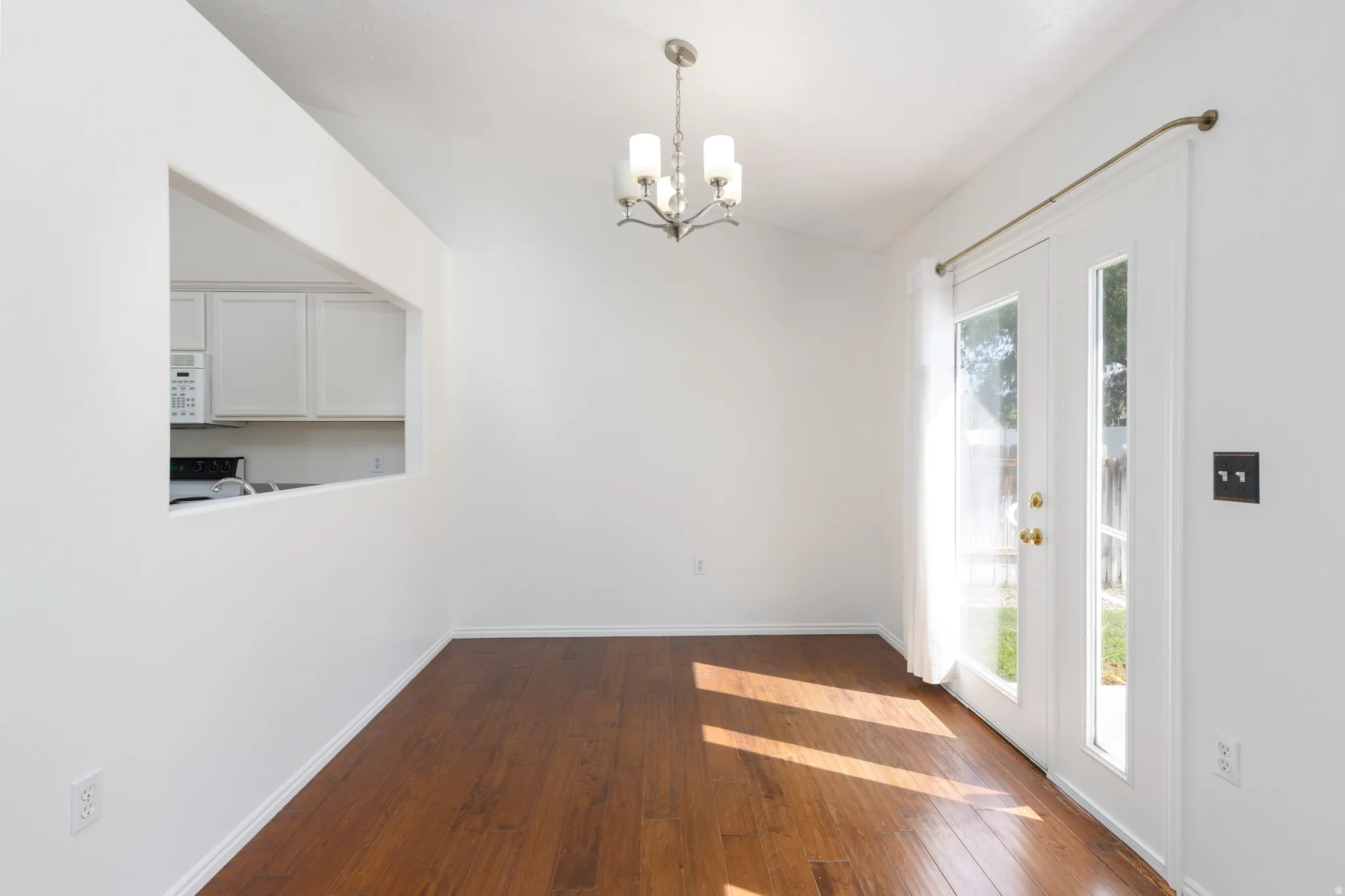Wood-finish flooring, vaulted ceiling, and a contemporary chandelier
