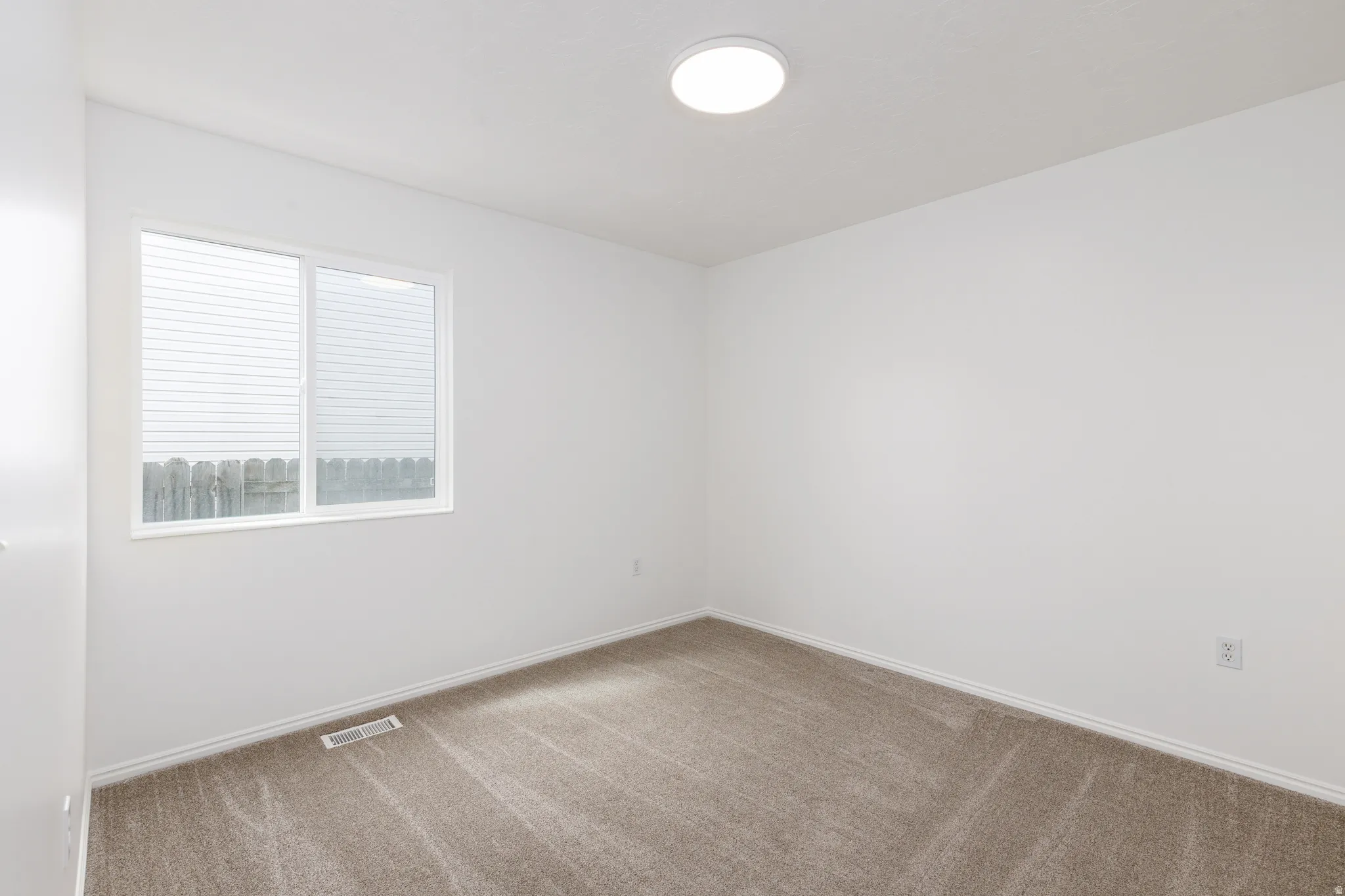Neutral wall paint, carpet flooring, flush mount ceiling light, white trim, and a window with horizontal blinds